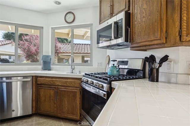 1334 Tourney Hill Ln Unit 61, Nipomo, CA 93444 - kitchen featuring appliances with stainless steel finishes, tile countertops, a sink, and light tile patterned flooring
