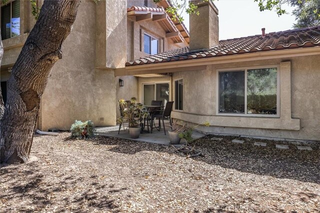 1334 Tourney Hill Ln Unit 61, Nipomo, CA 93444 - back of property featuring a patio area, a chimney, a tiled roof, and stucco siding
