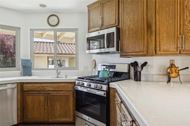 1334 Tourney Hill Ln Unit 61, Nipomo, CA 93444 - kitchen with stainless steel appliances, tile countertops, a sink, and brown cabinetry