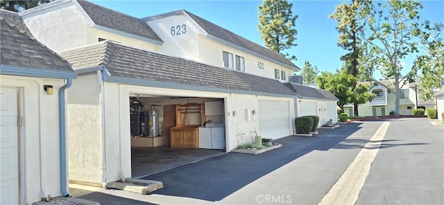 623 Church Pl Unit 3, Redlands, CA 92374 - view of home's exterior featuring separate washer and dryer, water heater, roof with shingles, and stucco siding