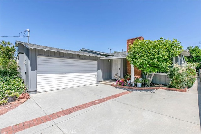 14719 Wyandotte St, Van Nuys, CA 91405 - view of front of house featuring a garage, a chimney, concrete driveway, and board and batten siding