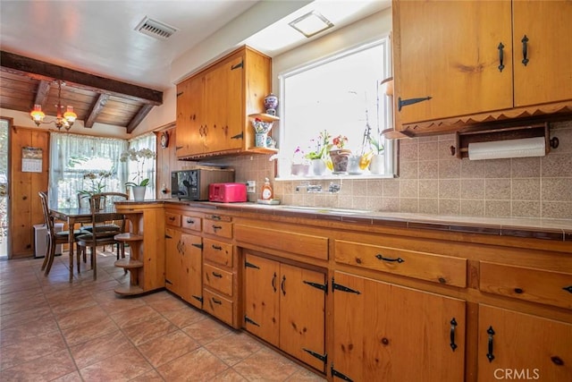 14719 Wyandotte St, Van Nuys, CA 91405 - kitchen featuring tile counters, backsplash, a sink, brown cabinetry, and black microwave