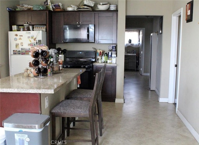 975 E Citrus St, Riverside, CA 92507 - kitchen with black appliances, dark brown cabinetry, a center island, baseboards, and a kitchen breakfast bar