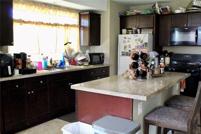 975 E Citrus St, Riverside, CA 92507 - kitchen featuring black appliances, a sink, a center island, a kitchen breakfast bar, and light stone countertops