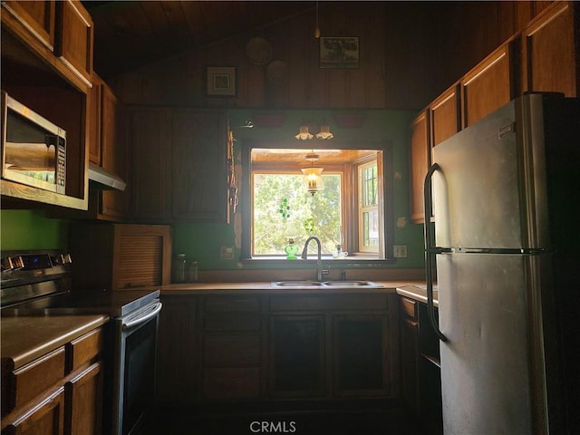 29348 123rd St E, Pearblossom, CA 93553 - kitchen featuring appliances with stainless steel finishes, a sink, under cabinet range hood, lofted ceiling, and brown cabinets
