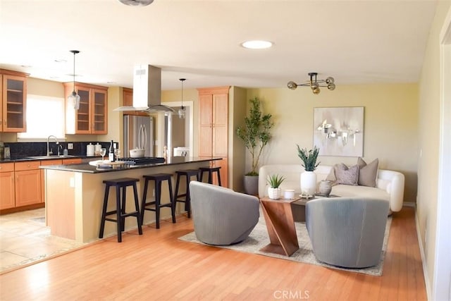 5 W 12th St, Paso Robles, CA 93446 - kitchen featuring island exhaust hood, freestanding refrigerator, a sink, a breakfast bar area, and dark countertops