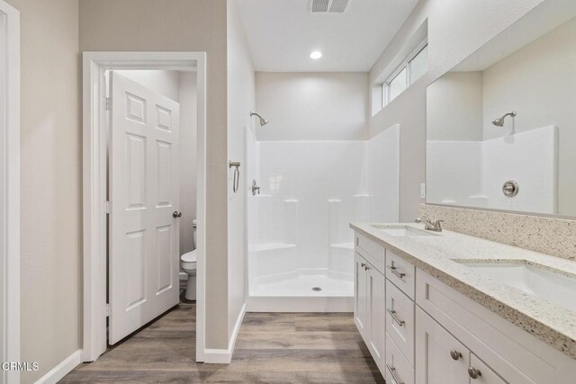 40719 E 171st St E, Lake Los Angeles, CA 93535 - bathroom with tiled shower, toilet, wood finished floors, baseboards, and double vanity