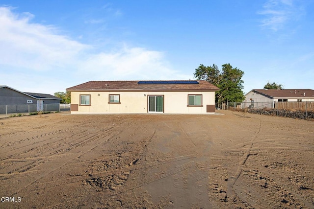 40719 E 171st St E, Lake Los Angeles, CA 93535 - rear view of house with roof mounted solar panels, fence, and stucco siding