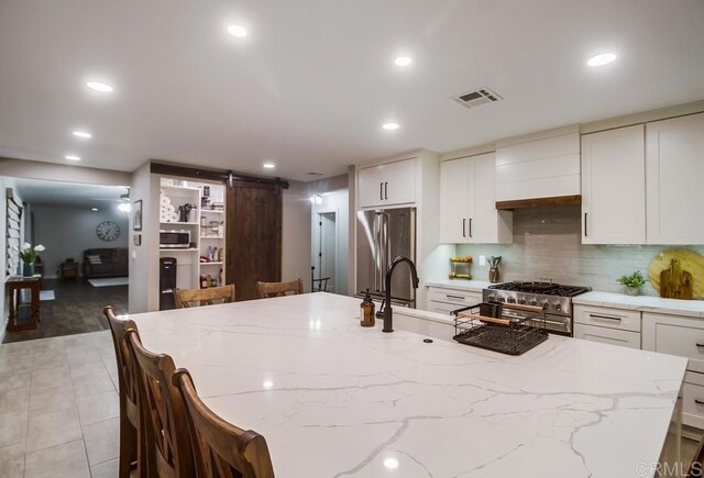 2444 Via Dieguenos, Alpine, CA 91901 - kitchen with appliances with stainless steel finishes, a barn door, recessed lighting, a large island with sink, and tasteful backsplash
