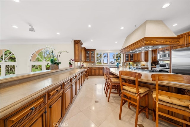 1502 Paseo La Cresta, Palos Verdes Estates, CA 90274 - kitchen featuring built in appliances, brown cabinetry, a breakfast bar, recessed lighting, and glass insert cabinets