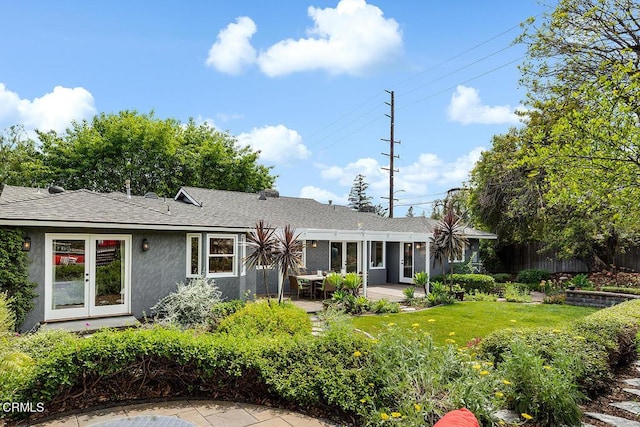 back of property with roof with shingles, stucco siding, and a patio