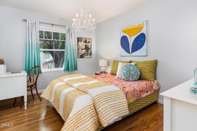 bedroom featuring wood finished floors, a chandelier, and baseboards