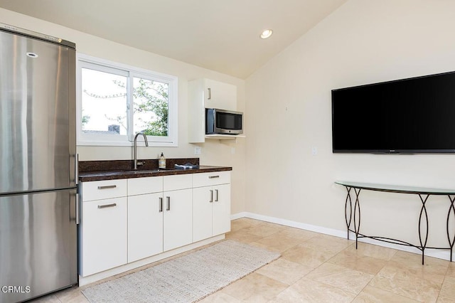 kitchen featuring stainless steel appliances, lofted ceiling, dark countertops, white cabinetry, and recessed lighting
