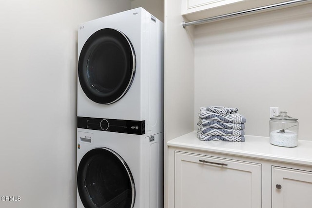 clothes washing area featuring stacked washer / dryer and cabinet space