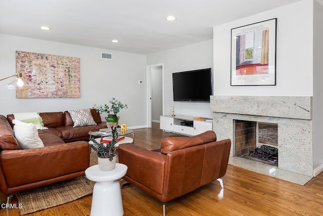 living area featuring wood finished floors, recessed lighting, baseboards, and a premium fireplace