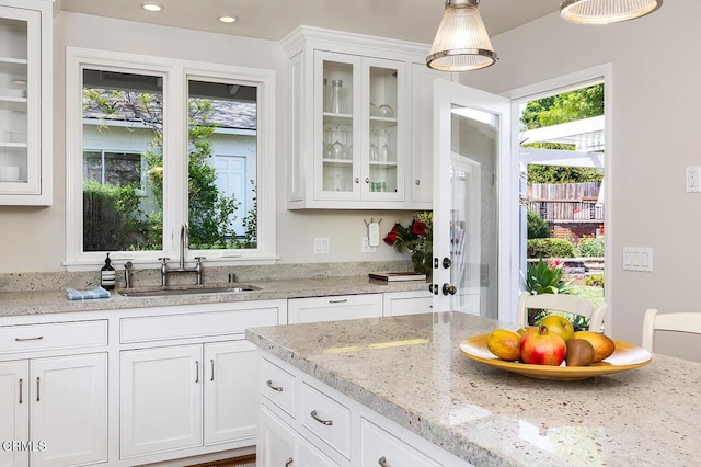 kitchen featuring a sink, white cabinetry, decorative light fixtures, light stone counters, and recessed lighting