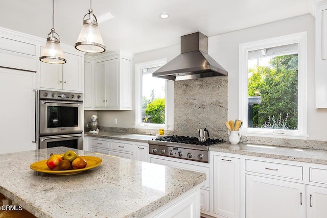 kitchen with wall chimney exhaust hood, appliances with stainless steel finishes, white cabinetry, backsplash, and recessed lighting
