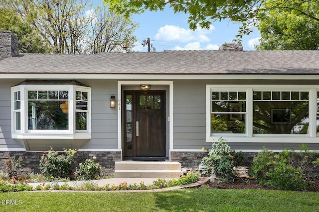 entrance to property featuring stone siding, a chimney, and a yard