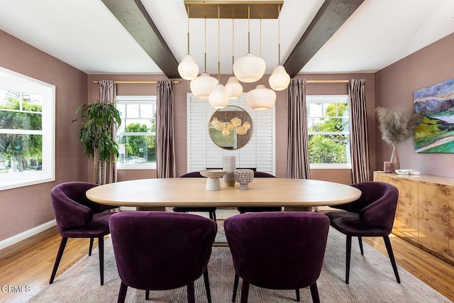 dining room with plenty of natural light, light wood-type flooring, beamed ceiling, baseboards, and a chandelier