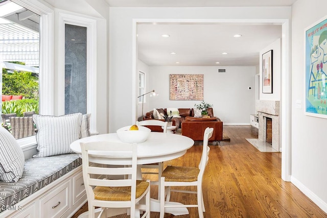 dining space with light wood finished floors, recessed lighting, a premium fireplace, and baseboards