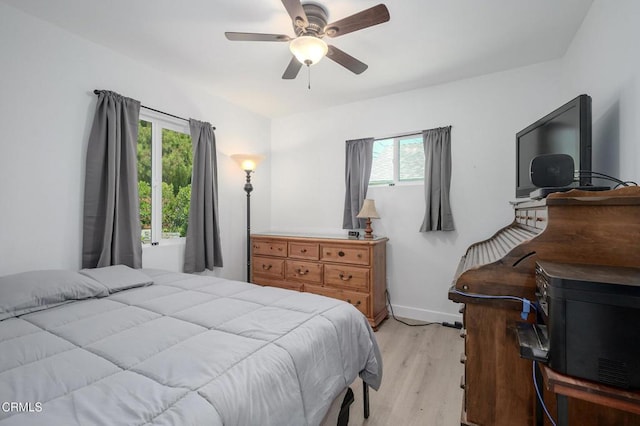 bedroom with light wood-style flooring, a ceiling fan, and baseboards