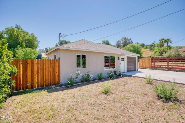 ranch-style house with driveway, stucco siding, an attached garage, and a shingled roof