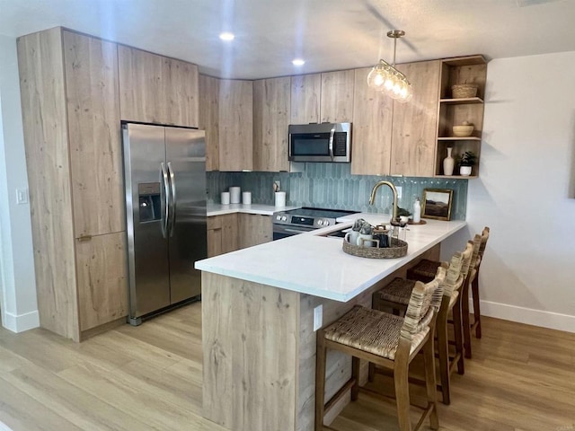 2041 Shadytree Ln, Encinitas, CA 92024 - kitchen with appliances with stainless steel finishes, a peninsula, light countertops, light wood finished floors, and a sink