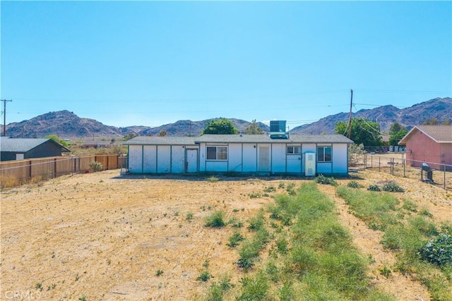 back of house with a mountain view and a fenced backyard