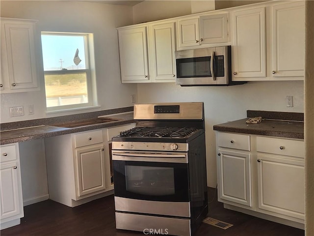 60824 Stagemans Rd, Landers, CA 92285 - kitchen with appliances with stainless steel finishes, white cabinets, dark countertops, and dark wood finished floors