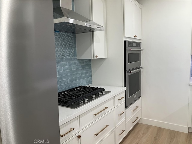 5331 E Ocean Blvd, Long Beach, CA 90803 - kitchen with wall chimney exhaust hood, stainless steel appliances, light wood-type flooring, decorative backsplash, and white cabinets
