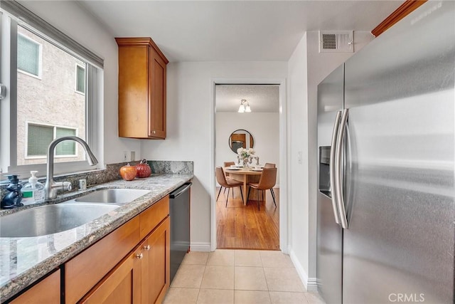 109 N Nicholson Ave Unit A, Monterey Park, CA 91755 - kitchen with stainless steel appliances, a sink, brown cabinets, light tile patterned floors, and light stone countertops