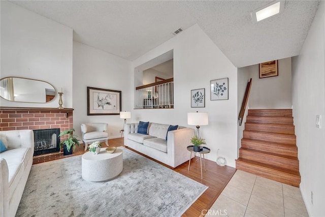 109 N Nicholson Ave Unit A, Monterey Park, CA 91755 - tiled living room featuring stairs, a fireplace, baseboards, and a textured ceiling