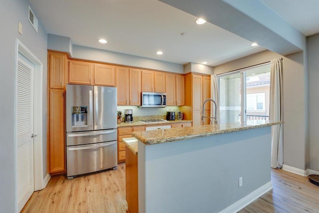 178 Via Montisi, Santee, CA 92071 - kitchen with appliances with stainless steel finishes, baseboards, light wood-type flooring, a kitchen island with sink, and light stone counters
