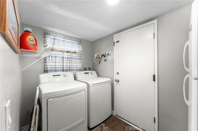 laundry room with washing machine and clothes dryer, dark wood-type flooring, and a textured ceiling