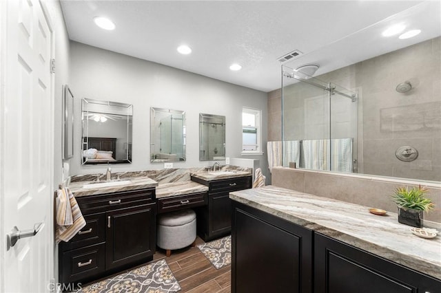 full bathroom with a shower stall, wood finished floors, vanity, and recessed lighting