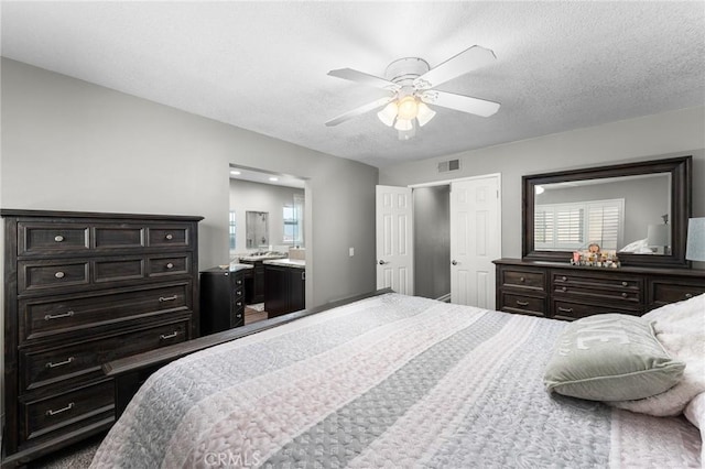 bedroom featuring a textured ceiling, ceiling fan, and ensuite bath