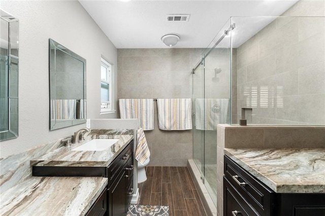 full bathroom featuring a shower stall, wood tiled floors, vanity, and tile walls