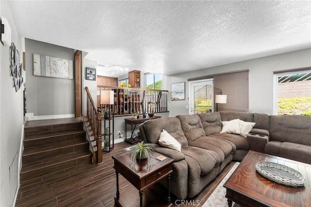 living room featuring baseboards, dark wood finished floors, stairs, a textured ceiling, and healthy amount of natural light