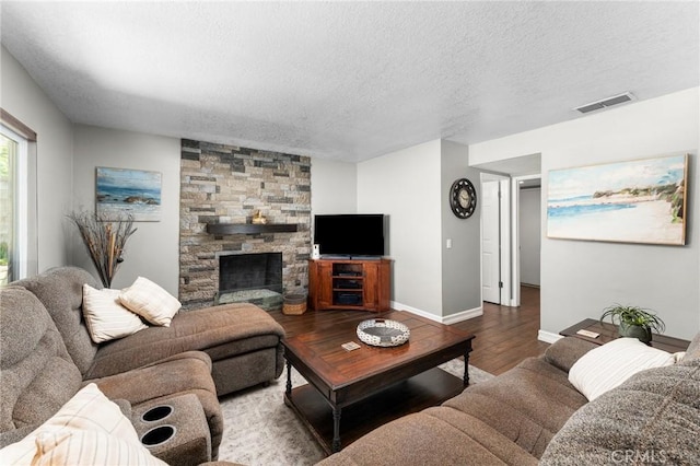 living area featuring wood finished floors, a textured ceiling, baseboards, and a fireplace