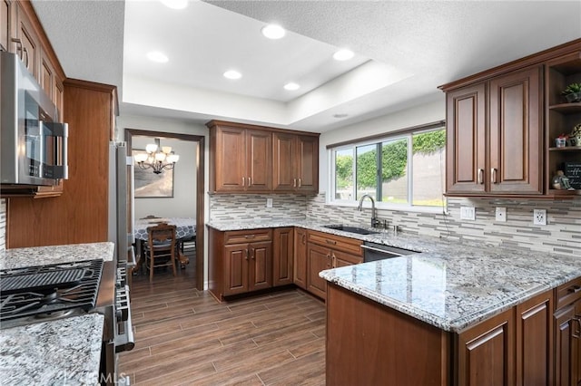 kitchen with a sink, appliances with stainless steel finishes, open shelves, tasteful backsplash, and a chandelier