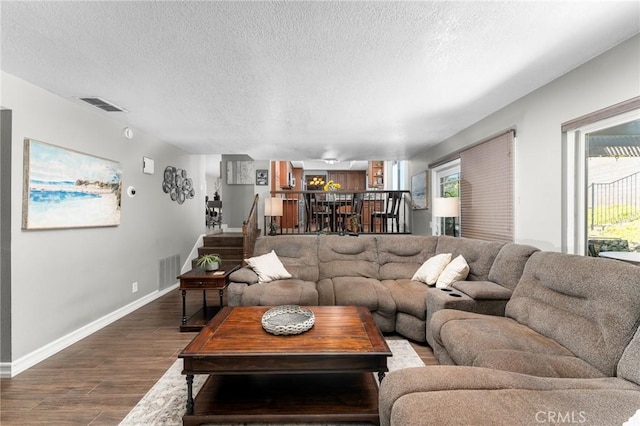 living room with dark wood-style floors, baseboards, and a textured ceiling