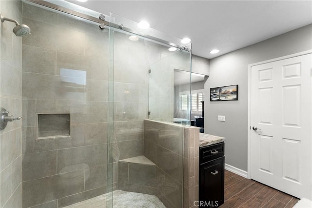 bathroom with wood tiled floors, a shower stall, vanity, baseboards, and recessed lighting