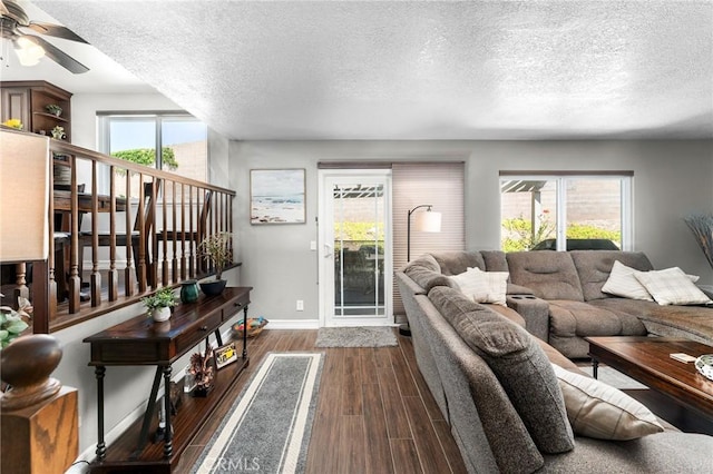 living area with baseboards, a textured ceiling, dark wood-style floors, a ceiling fan, and stairway