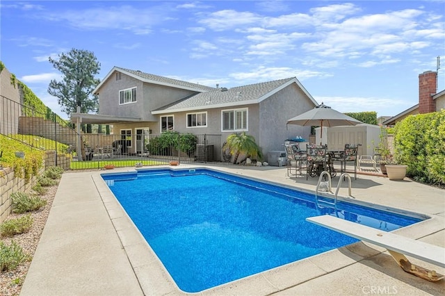 view of pool with a patio, fence, and a diving board