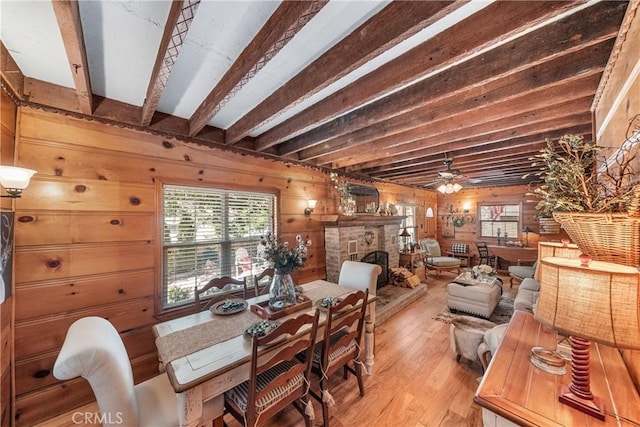 795 Glen View Ln, Twin Peaks, CA 92391 - dining room featuring wood walls, light wood-style flooring, a stone fireplace, beam ceiling, and ceiling fan