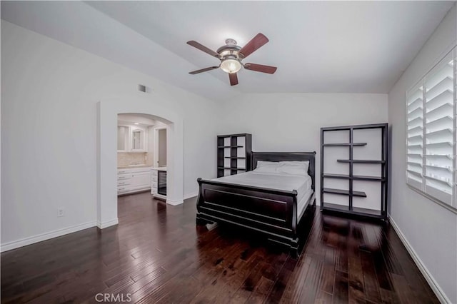 bedroom with wood finished floors, arched walkways, baseboards, and a ceiling fan