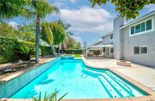 view of swimming pool featuring a patio, a pool with connected hot tub, and an outdoor fire pit