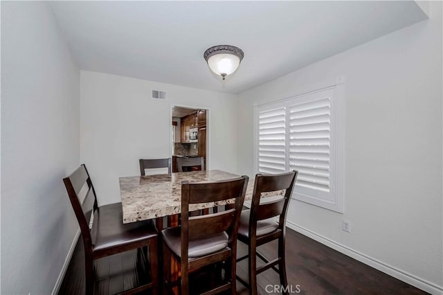 dining area with dark wood-type flooring and baseboards