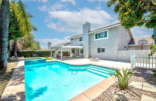 view of swimming pool featuring a patio, a fenced backyard, a pool with connected hot tub, and french doors