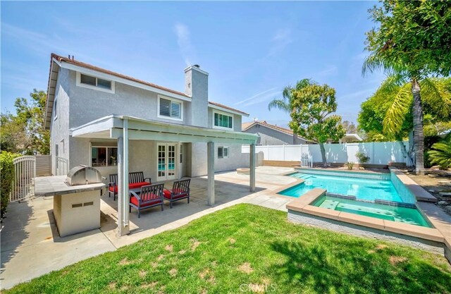 back of house with stucco siding, a patio area, a chimney, and a pool with connected hot tub